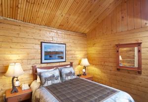 ein Schlafzimmer mit einem Bett in einem Blockhaus in der Unterkunft Grande Denali Lodge in McKinley Park