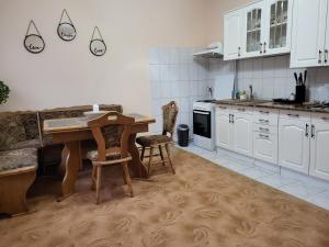 uma cozinha com armários brancos e uma mesa e cadeiras em Pandora Guest House em Cluj-Napoca