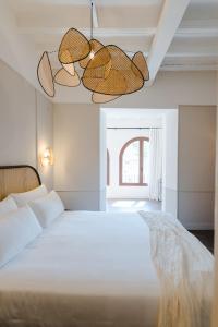 een slaapkamer met een wit bed en 2 hanglampen bij ORA Hotel Priorat, a Member of Design Hotels in Torroja