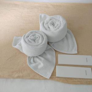 two white towels on a table next to a card at Victoria Sports Tower - Cozy Ambiance Condo Unit in Manila