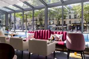 un restaurante con sillas rosas, mesas y ventanas en Hôtel Nude Paris - Color Vision, en París