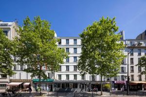 un edificio bianco con alberi di fronte di Hôtel Nude Paris - Color Vision a Parigi