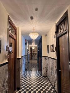a hallway with a checkered floor and a chandelier at Hotel Majestic in Kolkata
