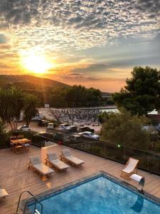 a swimming pool with a sunset in the background at Hotel Vila Park Bujari in Ksamil