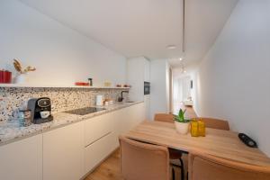 cocina con armarios blancos y mesa de madera en Georges & Madeleine Apartments, en Aalst