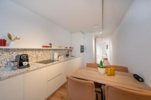 cocina con armarios blancos y mesa de madera en Georges & Madeleine Apartments en Aalst