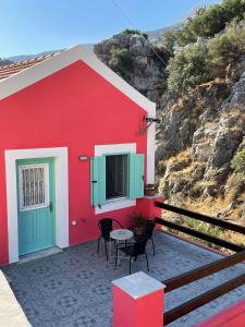 ein rotes und grünes Haus mit einem Tisch und Stühlen in der Unterkunft Casa Di Rosse in Symi