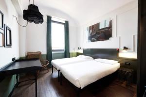 ein Schlafzimmer mit zwei Betten, einem Schreibtisch und einem Fenster in der Unterkunft Generator Rome in Rom