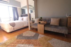 a bedroom with a bed and a couch and a mirror at Oasis Regency @ Acqua Livingstone near Rockwell in Manila