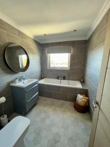 a bathroom with a tub and a sink and a mirror at Beachfront Penthouse, Largs in Largs