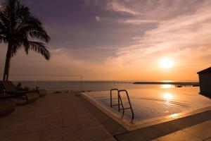a pool with a view of the ocean at sunset at Senagajima Island Resort & Spa in Tomigusuku