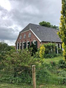 a large brick house with a fence in front of it at Boerderij woning in Aalten in de Achterhoek in Aalten