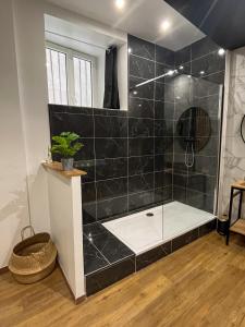 uma casa de banho com um chuveiro com azulejos pretos em Suite cocooning & spa em Béziers