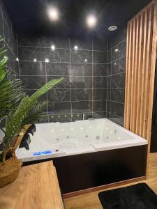 uma banheira na casa de banho com azulejos pretos em Suite cocooning & spa em Béziers