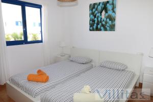 een witte slaapkamer met een bed met een oranje handdoek erop bij VILLA DUNIA by Villitas in Playa Blanca