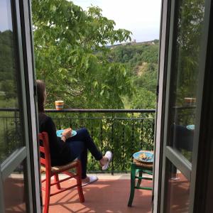 una donna seduta su una sedia su un balcone che guarda fuori dalla finestra di Casale Amerina a Camerata