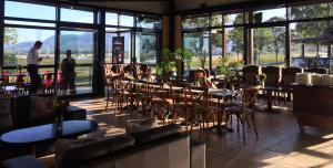 a restaurant with tables and chairs in a room with large windows at Estate Tuscany in Pokolbin