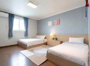 a bedroom with two beds and a window at Ellui Hotel Jeju in Jeju