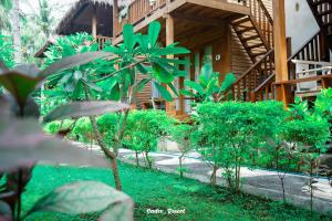 a garden with trees and plants in front of a building at Sadev Resort in Gili Trawangan