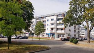 biały budynek z samochodami zaparkowanymi na parkingu w obiekcie Apt with 6 single beds w Świnoujściu
