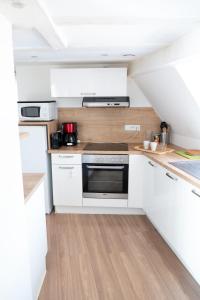 uma pequena cozinha com armários brancos e um fogão em SECRET MAMA with Aircon 150 meters from parking Rapp em Colmar