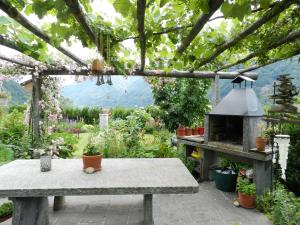 a garden with a table and a stone oven at CASA ALLA CASCATA House by the Waterfall and Garden of Senses in Maggia