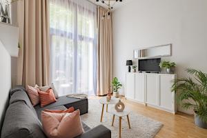 - un salon avec un canapé gris et une grande fenêtre dans l'établissement KAZ13 Kazinczy Apartment, à Budapest