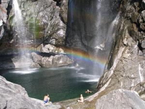 a group of people swimming in a pool with a rainbow at CASA ALLA CASCATA House by the Waterfall and Garden of Senses in Maggia