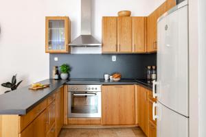 une cuisine avec des armoires en bois et un réfrigérateur blanc dans l'établissement KAZ13 Kazinczy Apartment, à Budapest