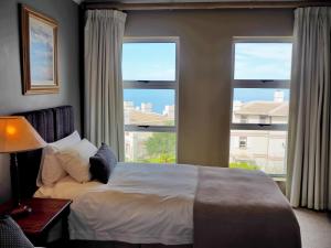 a bedroom with a bed and two large windows at DunPuttin - Pinnacle Point Golf Estate in Mossel Bay
