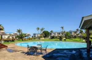 a swimming pool at a resort with chairs and a table at DunPuttin - Pinnacle Point Golf Estate in Mossel Bay