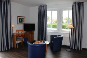 a living room with blue chairs and a table and a window at Hotel Altes Land in Jork