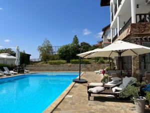a swimming pool with chairs and an umbrella next to a building at Комплекс «ТОП» in Sveti Vlas