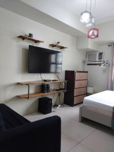 a room with a tv and a bed and a desk at Jojie's Crib Horizons101 Studio II in Cebu City