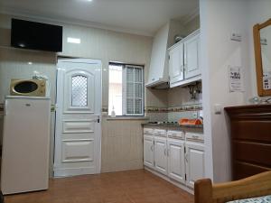 a kitchen with white cabinets and a white refrigerator at Estúdio Mário Fanha in Nazaré