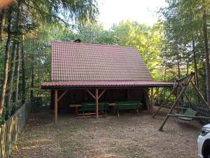 un pabellón con una mesa y bancos en un bosque en DOMEK LETNISKOWY MYSCÓWKA en Krempna