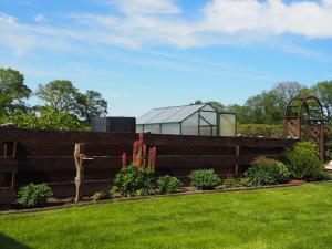 einen Garten mit einem Zaun und einem Glashaus in der Unterkunft Ferienhaus Irma 35530 in Uplengen