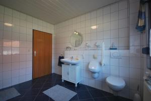 ein Badezimmer mit einem Waschbecken, einem WC und einem Spiegel in der Unterkunft Ferienhaus Irma 35530 in Uplengen