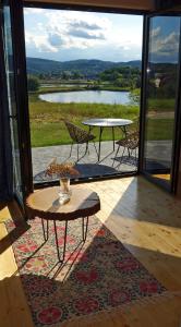 a patio with a table and chairs and a view of a lake at Domek Dzikie Lisko in Lesko