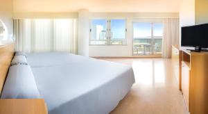 a bedroom with a large white bed and a flat screen tv at Hotel RH Gij&oacute;n & Spa in Gand&iacute;a