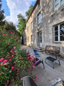 un edificio con un banco y flores delante de él en Les Hauts de St Jacques maison d'exception 300m2, jardin arboré 2000m2, en Pouzauges