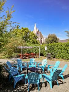 um grupo de cadeiras azuis e uma mesa num quintal em Le Grand Presbytère de Beaulieu em Beaulieu-lès-Loches