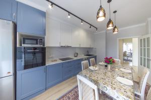 une cuisine avec des placards bleus et une table avec des chaises dans l'établissement Квартира посуточно Бизнес класса в ЖК АСЫЛ ТОБЕ, à Almaty