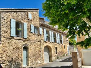 an old brick building with blue shuttered windows at La Villa 1777 in Lagnes