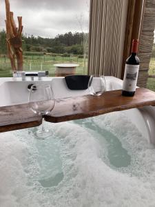a bottle of wine and two wine glasses in a bath tub at O REFUXIO DOS CEBREIROS in Mazaricos