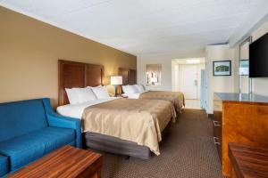 a hotel room with two beds and a blue couch at Quality Inn & Suites Oceanblock in Ocean City