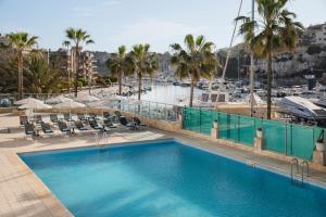 a large swimming pool with chairs and a marina at Porto Drach Aparthotel & Suites in Porto Cristo