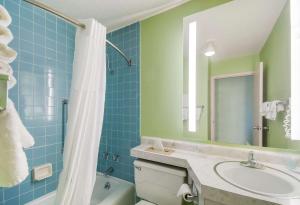 a bathroom with a tub and a sink and a mirror at Clarion Inn in Hurley