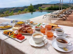 una mesa con alimentos para el desayuno y tazas de café en Relais Cocci Grifoni - Panoramic Wine Resort, en Offida