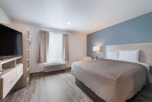 ein Hotelzimmer mit einem Bett und einem Flachbild-TV in der Unterkunft WoodSpring Suites Concord-Charlotte Speedway in Concord